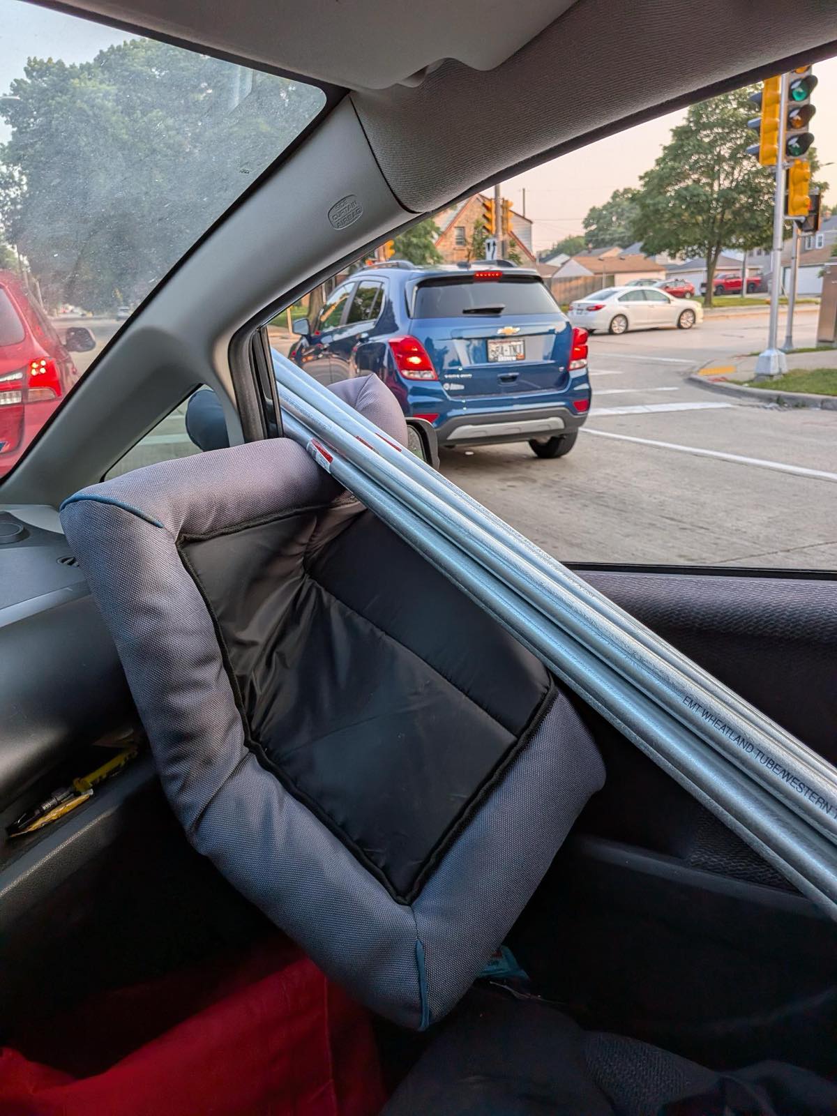 Ten-foot sticks of EMT conduit threaded through a Honda Fit at a stoplight
